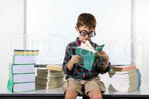 Boy reading book while sitting in classroom