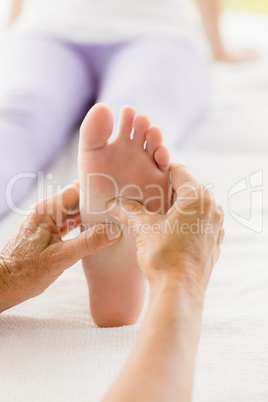 Cropped image of masseur giving foot massage to woman