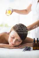 Midsection of masseur pouring oil on woman