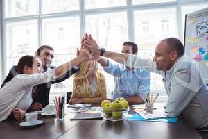 Coworkers giving high-five in meeting room