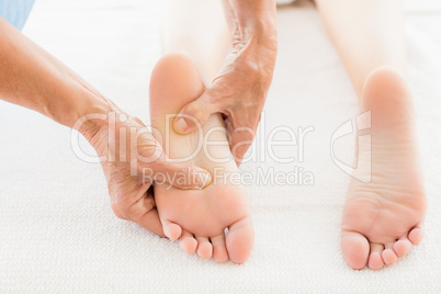 Cropped image of masseur giving foot massage to woman