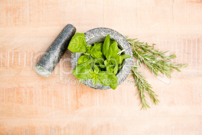 Mortar and pestle with basil and rosemary on table