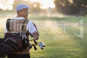 Rear view of mature man carrying golf bag