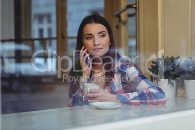 Young woman listening to cellphone at cafe