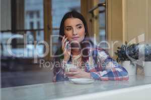 Young woman listening to cellphone at cafe
