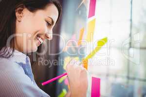 Happy creative businesswoman writing on sticky notes