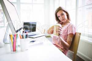 Portrait of tired graphic designer holding disposable coffee cup