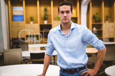 Confident businessman with hand on hip in meeting room