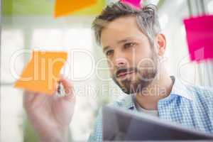 Young businessman writing on adhesive notes