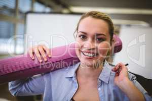 Happy businesswoman with bag and exercise mat