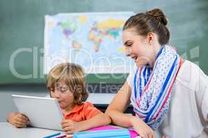 Teacher assisting boy using digital tablet