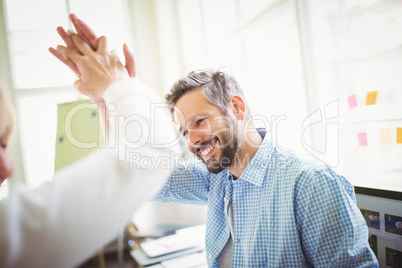 Happy coworkers giving high-five in creative office