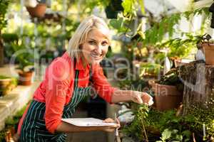 Female gardener with clipboard inspecting plants