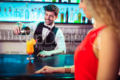 Bartender pouring cocktail in glass for customer