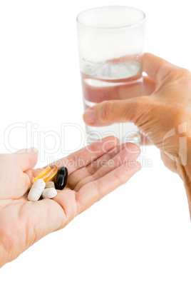 Person holding pills and glass