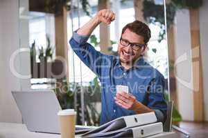 Portrait of excited businessman punching in air at office