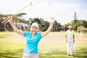 Portrait of cheerful golfer woman with arms raised