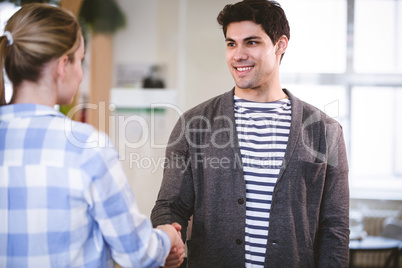 Handsome executive shaking hands with colleague at creative offi