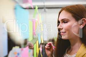 Close-up of businesswoman writing on sticky notes