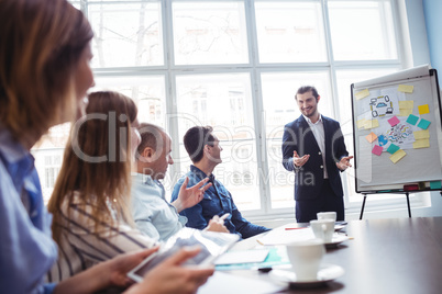 Coworkers looking at smiling businessman giving presentation