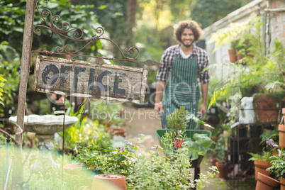 Office placard by plants while gardener in background