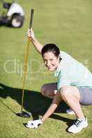 Woman holding golf club while crouching