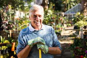 Portrait of happy gardener holding tool at garden
