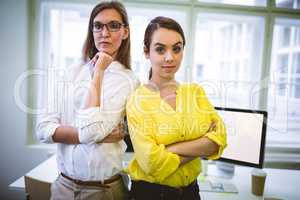 Portrait of confident colleagues standing with arms crossed at o