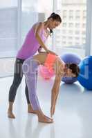 Full length of trainer assisting woman