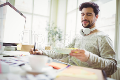 Businessman writing from note in office