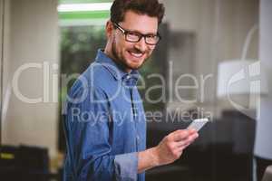 Portrait of happy businessman with mobile phone at creative offi