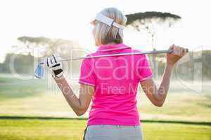 Rear view of woman golfer holding her club