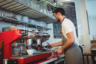 Side view of barista working by coffee maker at cafe