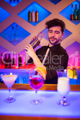 Bartender with cocktail shaker at bar counter