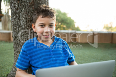 Portrait of boy using laptop at park