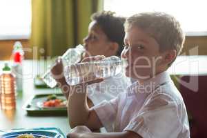 Portrait of schoolboy drinking water from bottle