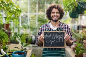 Happy bearded gardener holding open sign placard