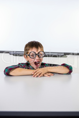 Boy yawning while sitting at table in classroom