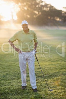 Smiling golfer with hand on hip while holding golf club