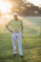 Smiling golfer with hand on hip while holding golf club