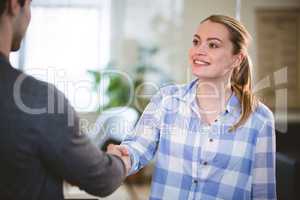 Happy executive shaking hands with colleague at creative office