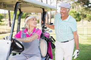 Golfer woman looking at man while sitting in golf buggy