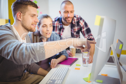 Businessman pointing on computer while discussing with colleague