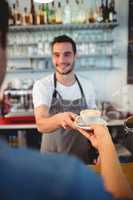 Customer taking coffee from happy waiter at cafe