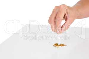 Cropped image of person holding broken cigarette at table