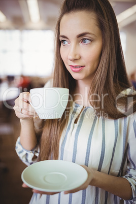 Young businesswoman having coffee at office cafeteria