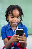 Smiling boy using mobile phone in classroom