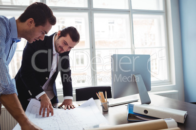 Interior designer discussing blueprint with colleague