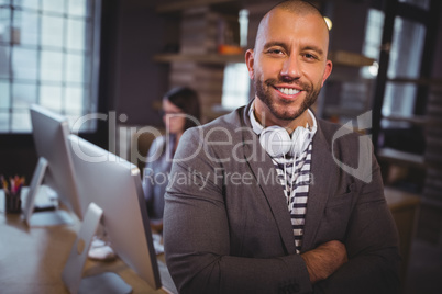 Confident creative businessman standing by desk