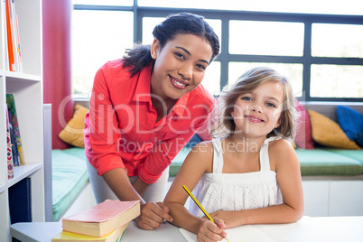 Portrait of teacher with girl in school library